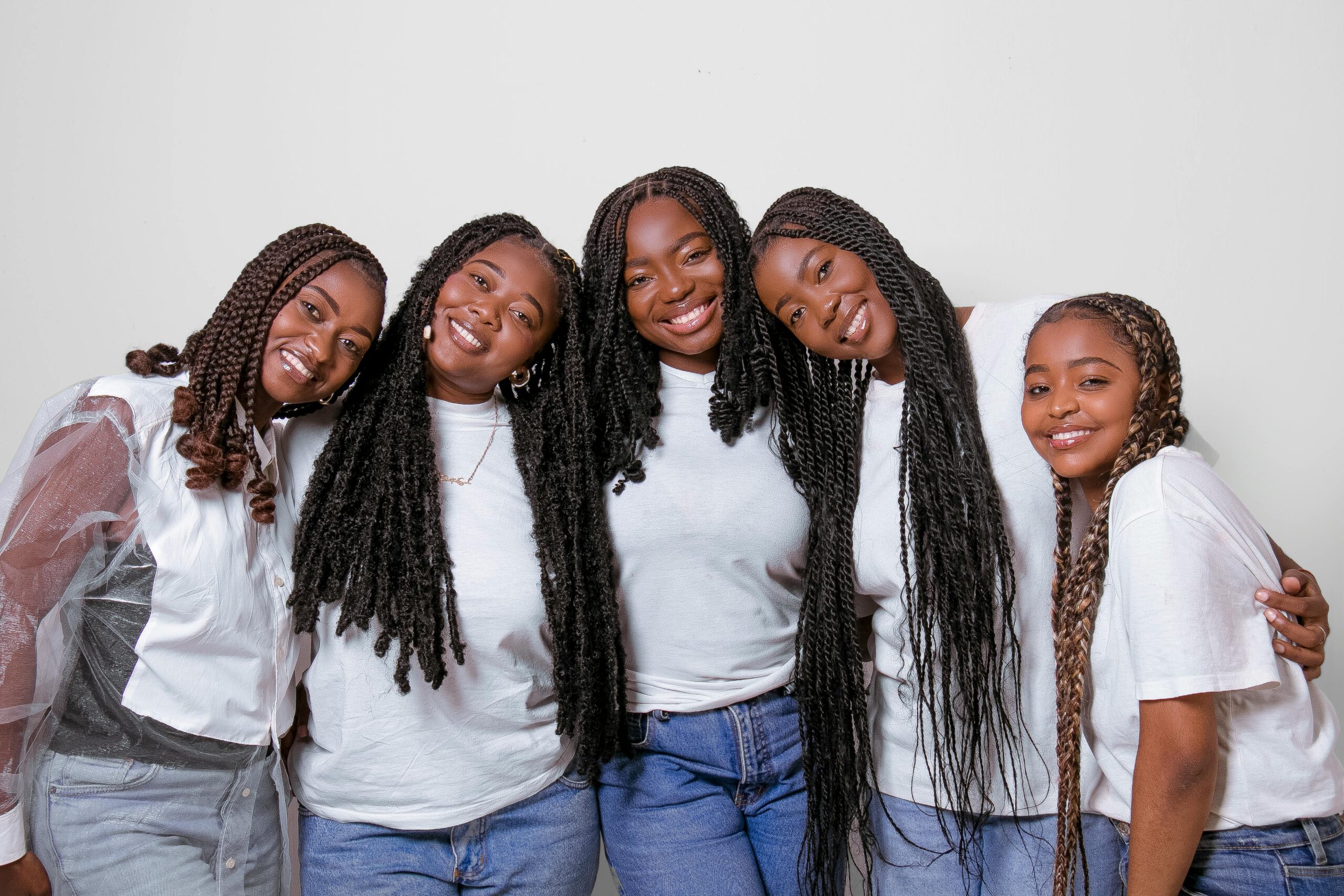 A cheerful group of five young black women happily posing together in casual outfits.