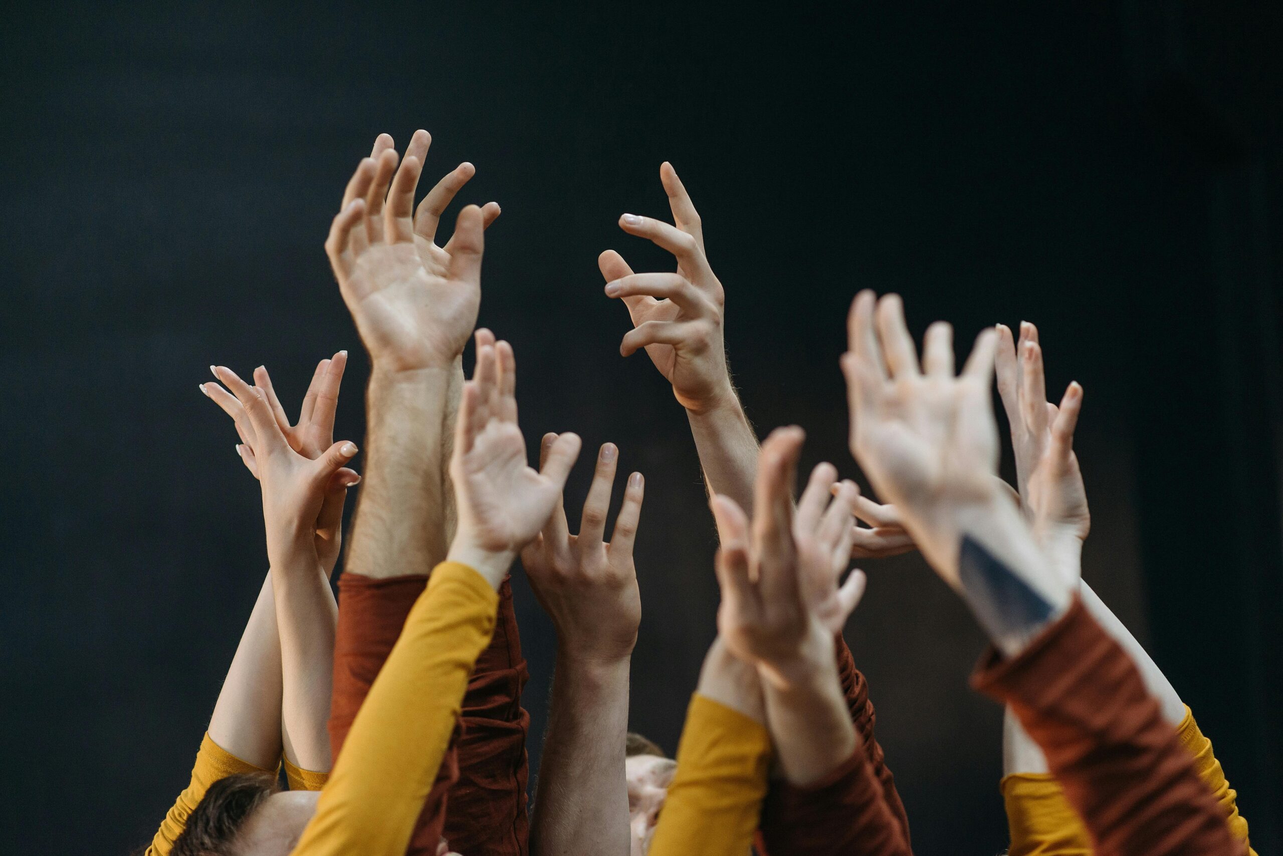 A vibrant image of raised hands symbolizing unity and movement against a dark background.